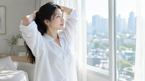 Woman Tying Hair by Window